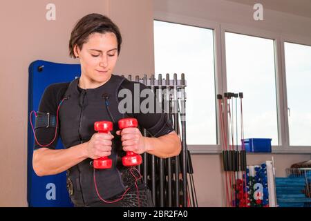 Junge Frau, die mit Hanteln in einem Fitnessstudio trainiert Stockfoto