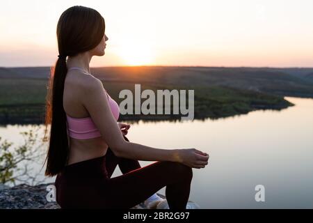 Gesundes Leben Übung Konzept - Frau praktiziert Pranayama Yoga Atemkontrolle in Lotus Pose padmasana im Freien in den Bergen am Morgen Stockfoto