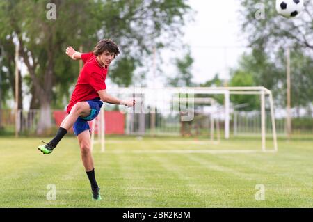 Fußballspieler Teenager kicks Ball in einem Tor Stockfoto