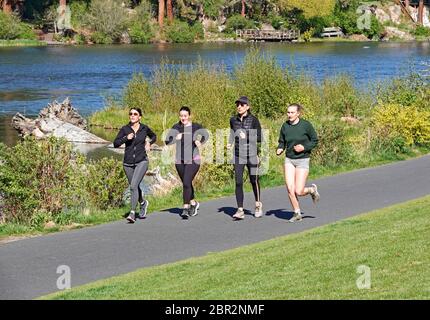 Eine Gruppe junger Frauen übt soziale Distanz aufgrund des Covid 19 Virus, während sie entlang des Deschutes River in Bend, Oregon laufen. Stockfoto