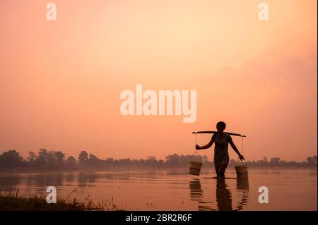 Die junge kambodschanische Frau sammelt Wasser in der Dämmerung in Srah Srang, einem alten Stausee in Angkor. Provinz Siem Reap, Kambodscha, Südostasien Stockfoto