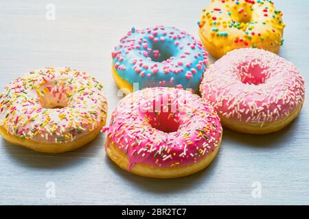 Verschiedene Donuts mit bunt mattierten, rosa Glasur und Streusel auf blauem Tisch. Platz für Text kopieren. Stockfoto