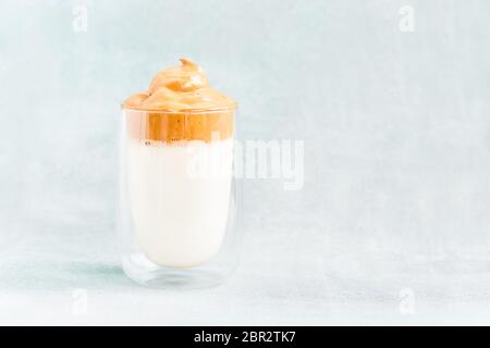 Trendy hausgemachten Dalgona Kaffee in Glas auf blauem Hintergrund. Rezept der beliebten koreanischen Getränk Latte mit Schaum von Instant-Kaffee. DIY, Anleitung. Stockfoto