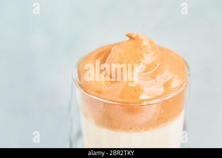 Oberseite des Dalgona Kaffees in einem transparenten Glas auf hellblauem Hintergrund. Kopierbereich für Text, selektiver Fokus Stockfoto