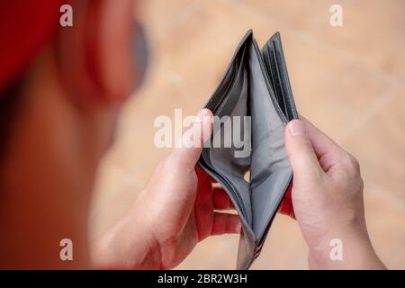 Ein Mann ohne Geld, der arbeitslos und bankrott ist, schaut in seine leere Brieftasche. Stress aus der Covid-19-Krise, arbeitslose Geschäftsleute warten auf neue Arbeitsplätze, Stockfoto