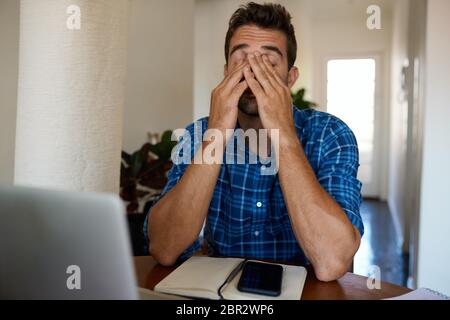 Mann, der müde aussieht, während er fern von zu Hause arbeitet Stockfoto