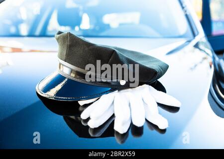 Der schwarze Chauffeur Kappe und ein Paar weiße Hand Handschuhe auf Motorhaube Stockfoto