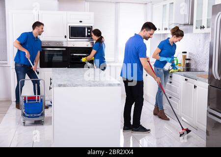 Gruppe von Jungen Hausmeister in Uniform Reinigung Küche zu Hause Stockfoto