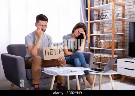 Junges Paar sitzt auf einem Sofa mit Hilfe Anmelden bei der Berechnung der Rechnung Stockfoto