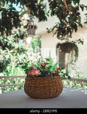 Weidenkorb mit Blumen auf dem Tisch gefüllt. Korb mit künstlichen Blumen auf Vernada. Stockfoto
