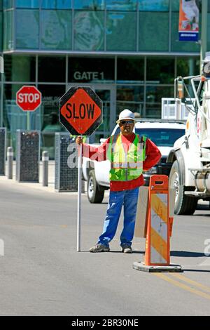 Der Verkehrskontroller steht auf der Straße mit einem "Slow"-Schild mit einem "Stopp"-Schild hinter ihm in Tucson AZ Stockfoto