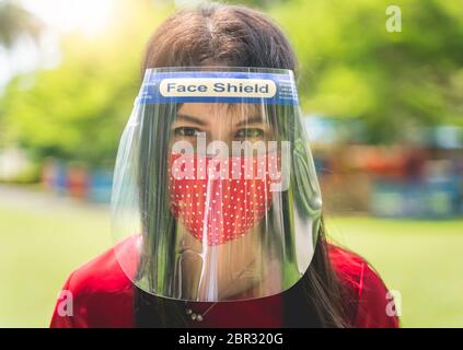 Frauen tragen Gesichtsschutz, asiatische Frauen verwenden Gesichtsschutz und Stoffmasken, um Infektionen zu verhindern und das Risiko während des Ausbruchs zu reduzieren und eine neue Norm zu verwenden Stockfoto