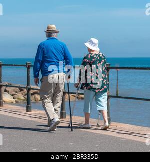 Ein Paar schlendern entlang der Esplanade in Sidmouth und genießen die heiße Sonne vor dem Feiertagswochenende. Quelle: DWR/Alamy Live News Stockfoto