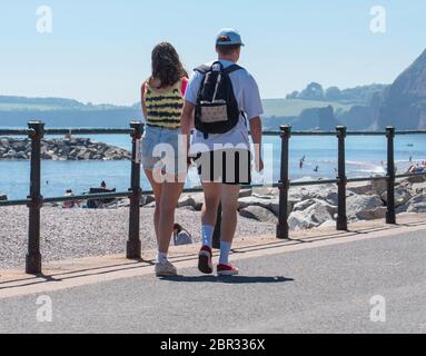 Ein junges Paar schlendert entlang der Esplanade in Sidmouth und genießt den heißen Sonnenschein vor dem Feiertagswochenende. Quelle: DWR/Alamy Live News Stockfoto