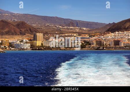 Blick von der Fähre auf den Atlantik und die Südküste von teneriffa, playa de los americas und los christianos. Dunkelblaues Wasser, weißes Spray Stockfoto