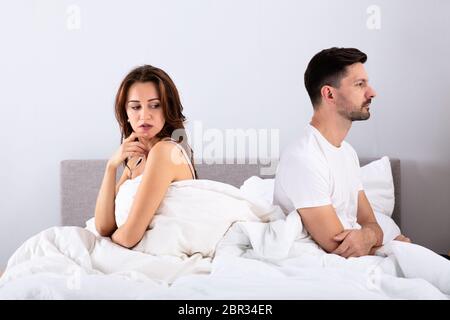Seitenansicht des Verzweifelten Ehepaar Rücken an Rücken auf dem Bett Stockfoto