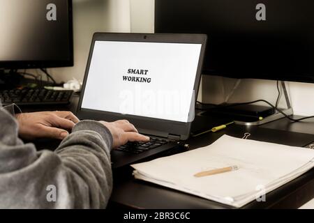 Rückansicht des Mannes, der ein Notebook für intelligentes Arbeiten von zu Hause aus verwendet. Smart Working auf dem Display geschrieben. Agiles Arbeitskonzept. Stockfoto