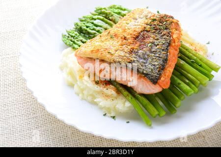 Gegrillter Lachs garniert mit Spargel und Kräutern und Kartoffelbrei, serviert auf weiß beschichtet. Stockfoto