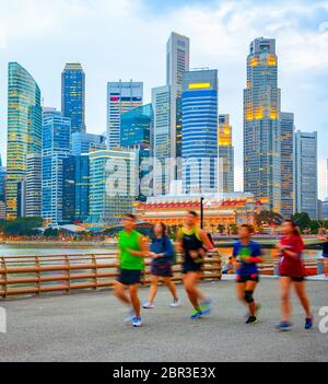 Menschen joggen in Singapur Damm, Abend City Skyline im Hintergrund Stockfoto