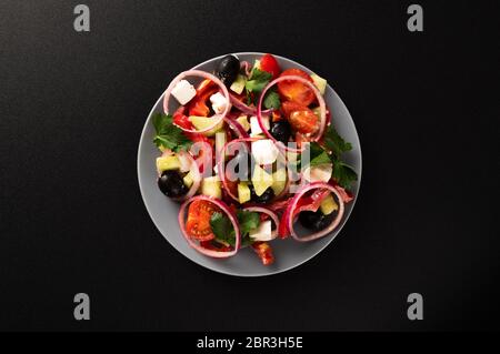 Griechischer Salat mit Oliven auf schwarzem Hintergrund. Blick von oben. Stockfoto