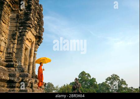 Ein Mönch steht mit Sonnenschirm vor einem Tempel bei Roluos. Angkor, UNESCO-Weltkulturerbe, Provinz Siem Reap, Kambodscha, Südostasien Stockfoto