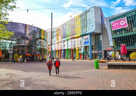 Amsterdam, Niederlande - 27. April 2019: Geschäftsviertel in der niederländischen Hauptstadt. Geschäftshäuser und Hotels mit bunten Fassaden. Menschen auf der Straße, das tägliche Leben. Stockfoto