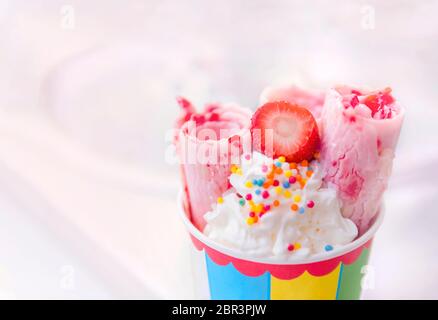 Eiswürfel mit Erdbeeren in einer papierfarbenen Tasse auf weißem Hintergrund. Erdbeereis. Gerolltes Eis, handgemachtes Eis Dessert. Stockfoto