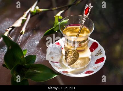 Türkischer Apfeltee und süßes (türkisches) Gebäck, serviert auf einem Glastisch im Garten Stockfoto