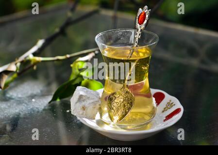 Türkischer Apfeltee und süßes (türkisches) Gebäck, serviert auf einem Glastisch im Garten Stockfoto