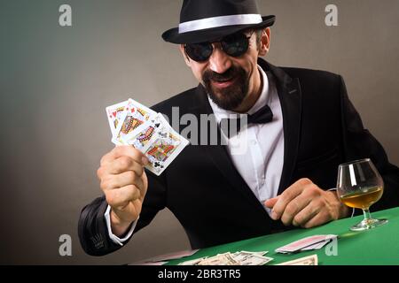 Der erfolgreiche elegante Spieler hat das Vierling im Pokerkartenspiel im Casino auf grauem Hintergrund, Spielkonzept. Stockfoto