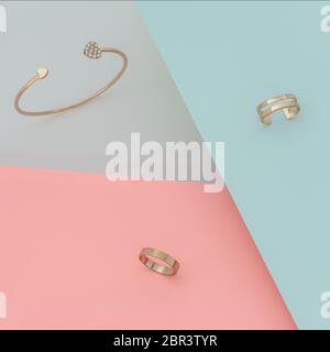 Golden mit Diamant-Armband und goldenen Ringen auf blauem und rosa Papier Hintergrund Stockfoto