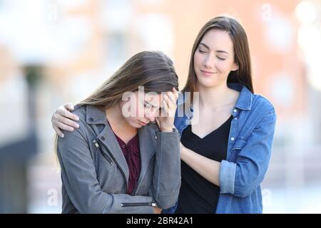 Heuchler schlecht Frau trösten Sie traurig Freund, der in der Straße beschwert, Stockfoto