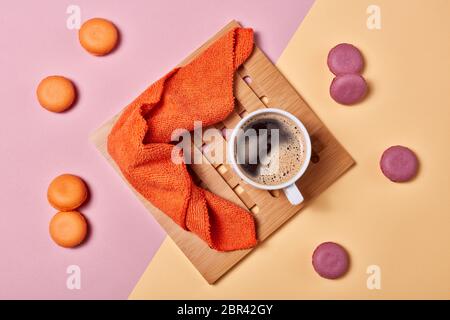 Stillleben mit einer Tasse Kaffee und köstlichen Makronen auf dem Hintergrund, bestehend aus zwei Farben rosa und gelb. Draufsicht. Designelement für Menü Stockfoto