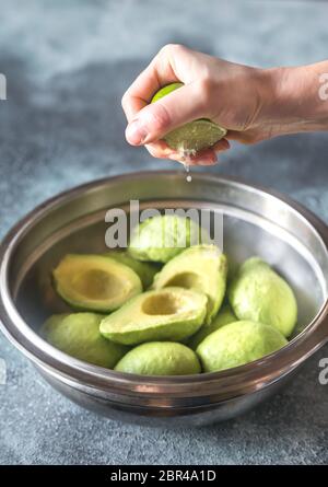 Hand zusammendrücken Kalk auf halbierte Avocados Stockfoto