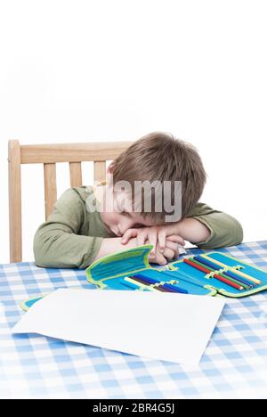 Ein Junge Kind müde und kämpfen mit den Belastungen des schriftliche Hausaufgaben. Stockfoto