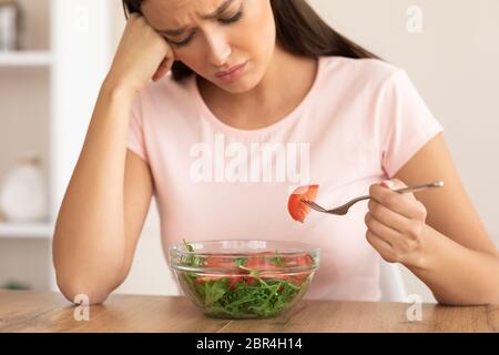 Traurige Frau, Die Salat-Slimming Zu Hause Am Tisch Sitzt Stockfoto