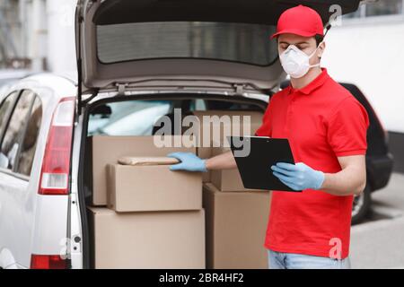 Schnelles Konzept für die automatische Bereitstellung. Kurier prüft Paket im Auto und Tablet Stockfoto