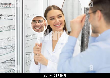 Optometriker hilft Mann, Korrektur Brille zu wählen Stockfoto