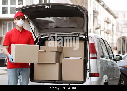 Viele Aufträge, viele Lieferkonzepte. Kurier hält großes Paket in der Nähe des Autos Stockfoto