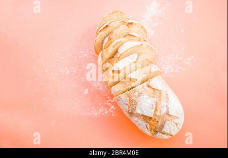 Frisch gebackenes Vollkorn-Brot mit Mehl auf orangefarbenem Hintergrund mit Copyspace bedeckt. Food Konzept. Stockfoto