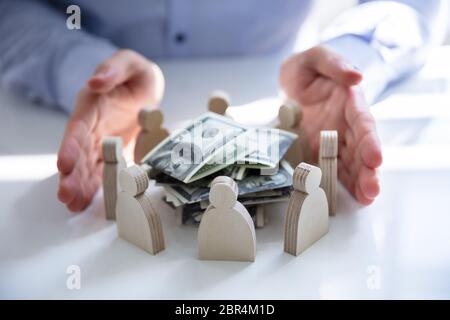 Die schützende Hand gestapelt Banknoten durch die menschlichen Figuren umgeben Stockfoto