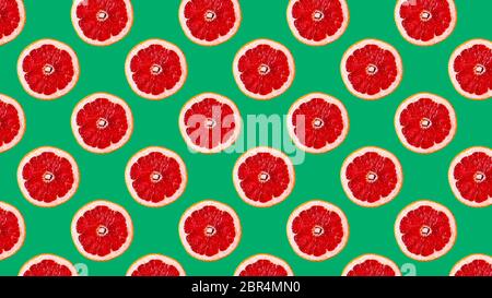 Nahtloses Muster mit Scheiben von roten Grapefruit auf grünem Hintergrund, Panorama-Format gemacht. Frische grüne Äpfel auf grünem Hintergrund isoliert. Obst-Patt Stockfoto