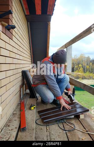 Der Master schneidet das Blech auf der gezeichneten Linie, um die Traufe zu installieren.2020 Stockfoto