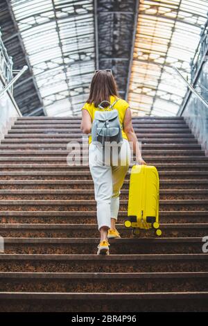 Frau mit gelber Tasche, die am Bahnhof über eine Treppe hinaufgeht Stockfoto