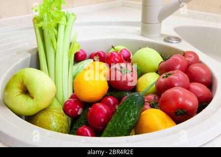 Waschen von Obst und Gemüse in Waschbecken nach dem Einkaufen aus dem Lebensmittelgeschäft während Coronavirus Covid-19 Quarantäne-Periode. Konzept der Sicherheit, Vorsichtsmaßnahmen, Stockfoto