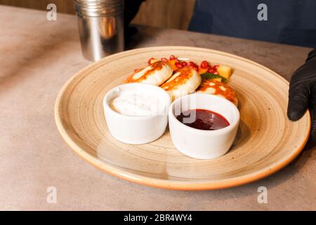 Quark Pfannkuchen mit Himbeermarmelade auf dem Teller. Käsekuchen mit Marmelade. Gesundes, leckeres Frühstück. Stockfoto