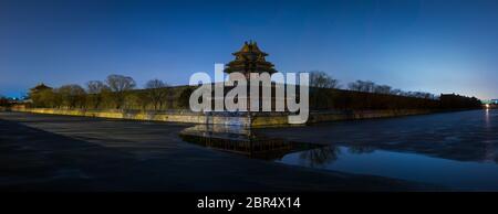 Panorama-Nacht Blick auf den nordwestlichen Turm und die Wände des Verbotenen Stadtpalastmuseums, die sich im halbgefrorenen Graben in Peking, China, spiegeln Stockfoto