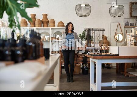 Lächelnde asiatische Frau in ihrem trendigen Haushaltswaren Geschäft stehen Stockfoto
