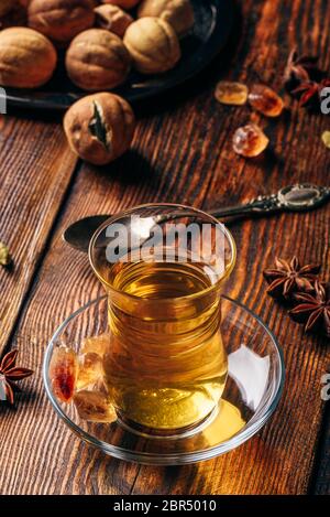 Gewürzten Kaffee mit Kardamom, Sternanis und getrocknete Kalk in der orientalischen Glas über Holz- Oberfläche Stockfoto