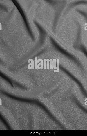Schwarz-weiß gewellter Seidenstoff mit Falten. Mockup und blank Designer für die Herstellung einer Flagge auf einem grauen Hintergrund Textur. Stockfoto